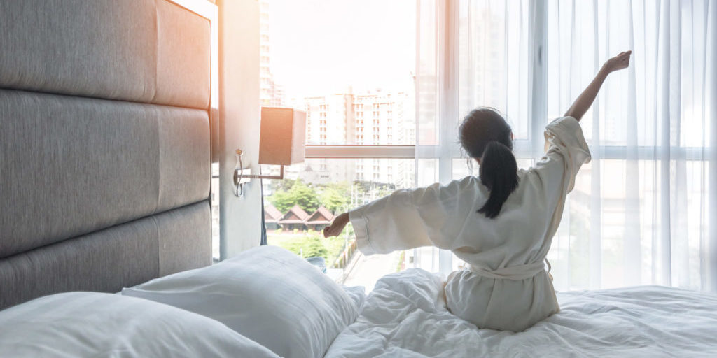 Work-life quality balance concept with lifestyle of Asian girl on bed, lazily relaxing in comfort bedroom in city hotel, take it easy, resting waking up from good sleep in weekend morning having a good day